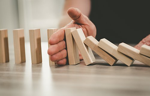 Hand verhindert Dominoeffekt von Holzteilen